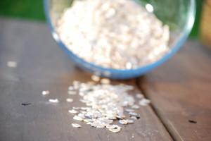 Oatmeal spilling out of bowl onto a wooden table