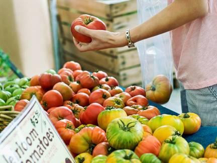 Hand picking up a tomato at the supermarket