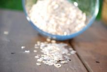 Oatmeal spilling out of bowl onto a wooden table