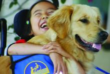 Young child hugging dog in service vest